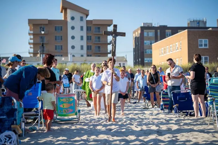 A processional cross made from the wood left over from the Long Island boardwalk destroyed by Hurricane Sandy in 2012 is carried across the sand ahead of Sunday Mass as part of the Beach Catholic initiative on Long Island on July 6, 2025. (photo: Joseph Ciorra / Beach Catholic )